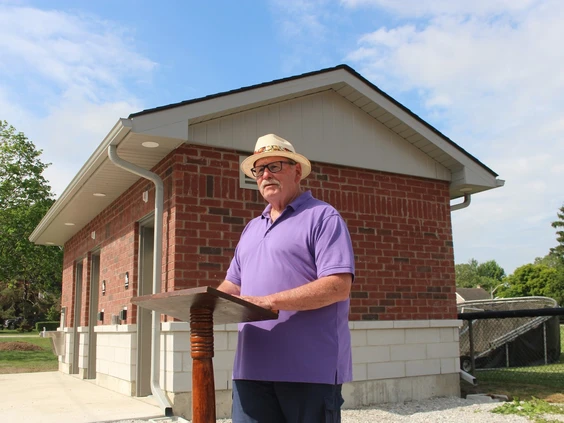 A man speaks at a lectern in front of a building