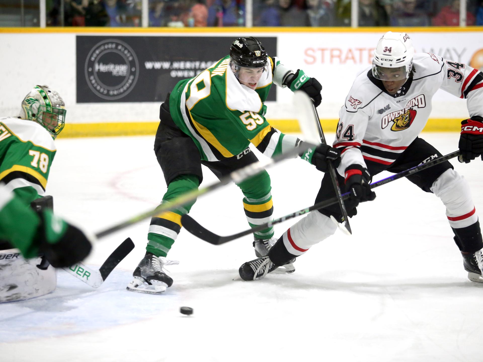 Oliver Bonk and Harry Nansi fight for the puck in front of Alexei Medvedev in the first period of a game between the Owen Sound Attack and London Knights.