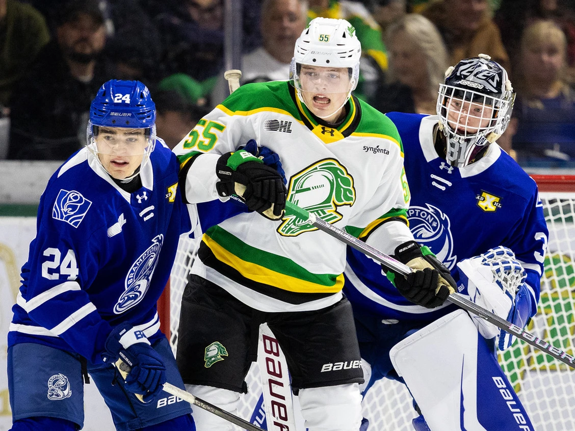 Rene Van Bommel of the London Knights stands in front of Mississauga Steelheads' net, goalie and a defenceman.
