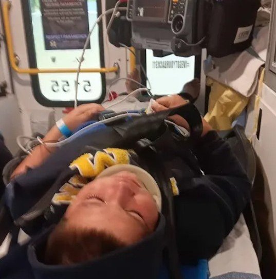 A young boy lying on a stretcher inside an ambulance