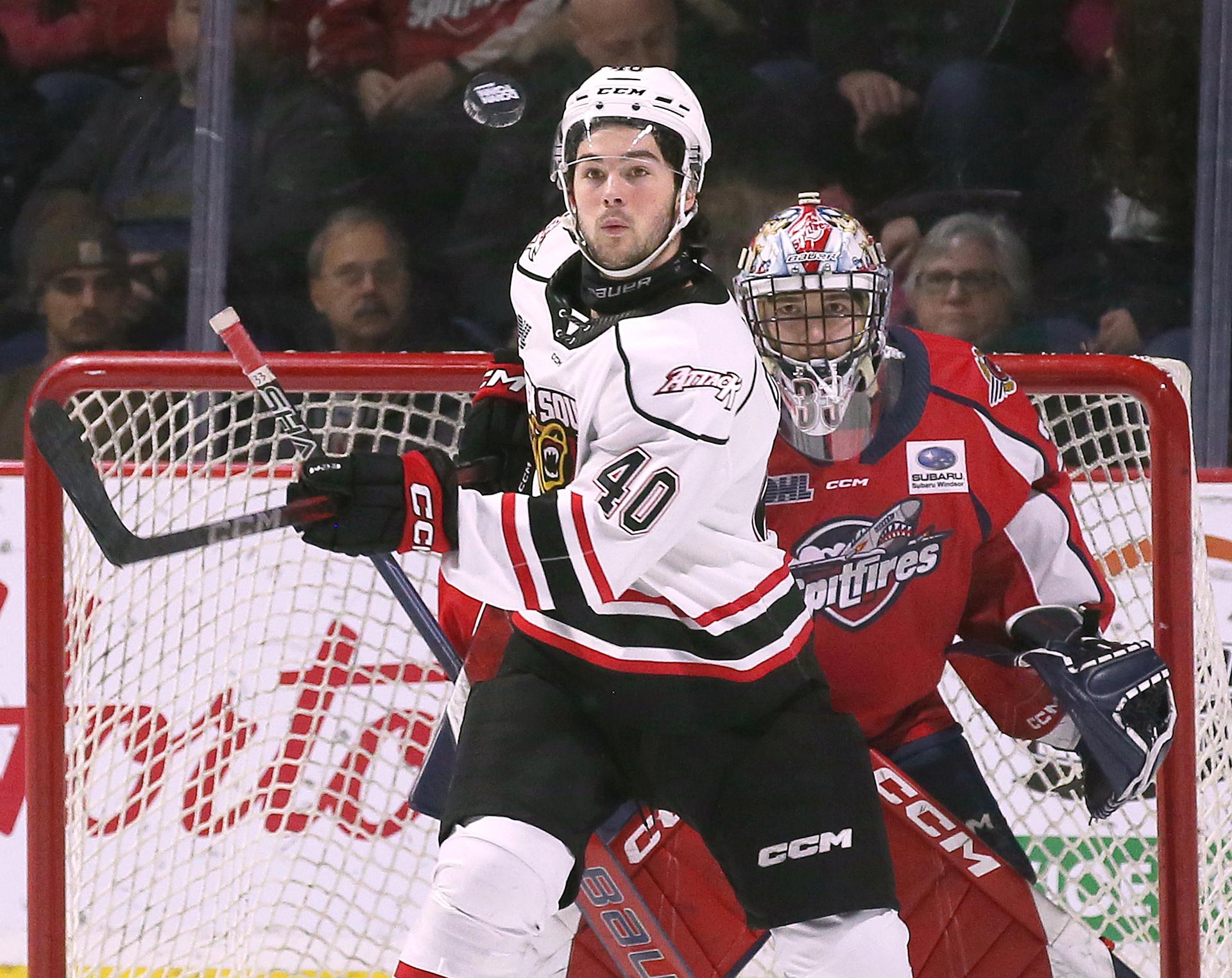 Owen Sound Attack forward Tristan Delisle and Windsor Spitfire goalie Joey Costanzo keep an eye on a high-flying puck during an OHL game.