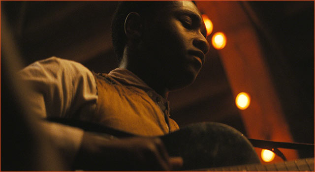 A person playing the guitar in SINNERS.