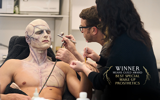 Jacob Elordi getting his makeup done for FRANKENSTEIN. Text over reads: Winner Muahs Guild Award Best Special Make-up Prosthetics.