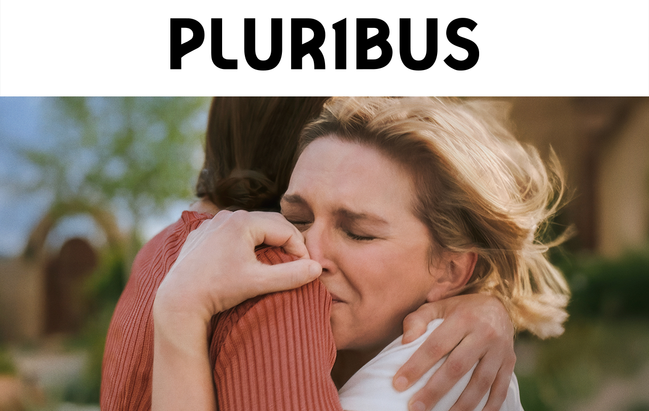 A still of two actors hugging in PLURIBUS. Text over reads: PLURIBUS.