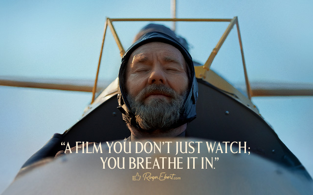 A person flying in an old fashioned yellow plane. Text over reads: 