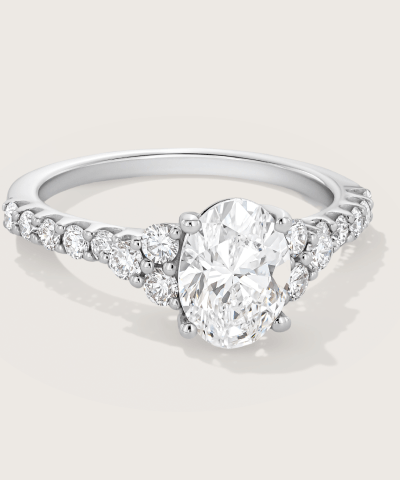 White gold engagement ring featuring an oval diamond center stone and a pavé diamond band.
