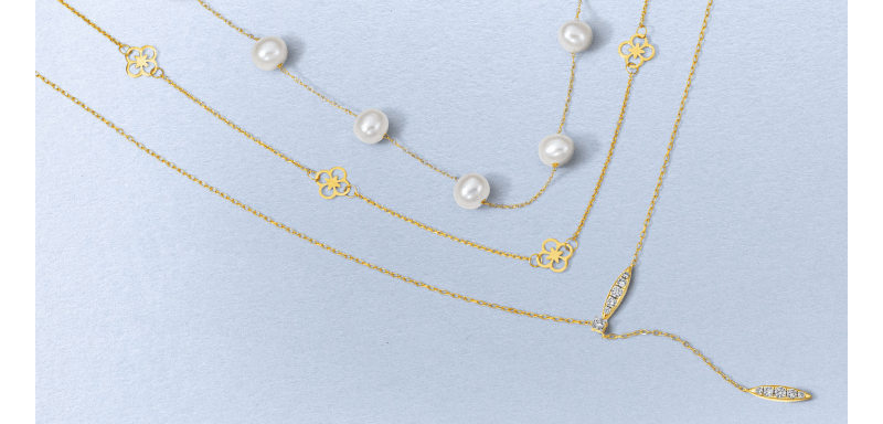 Layered yellow gold necklaces featuring pearls, clover motifs and diamond accents.