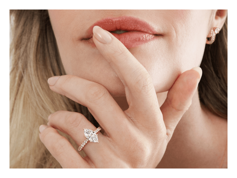 Woman wearing a marquise-shaped diamond engagement ring with a pavé band.