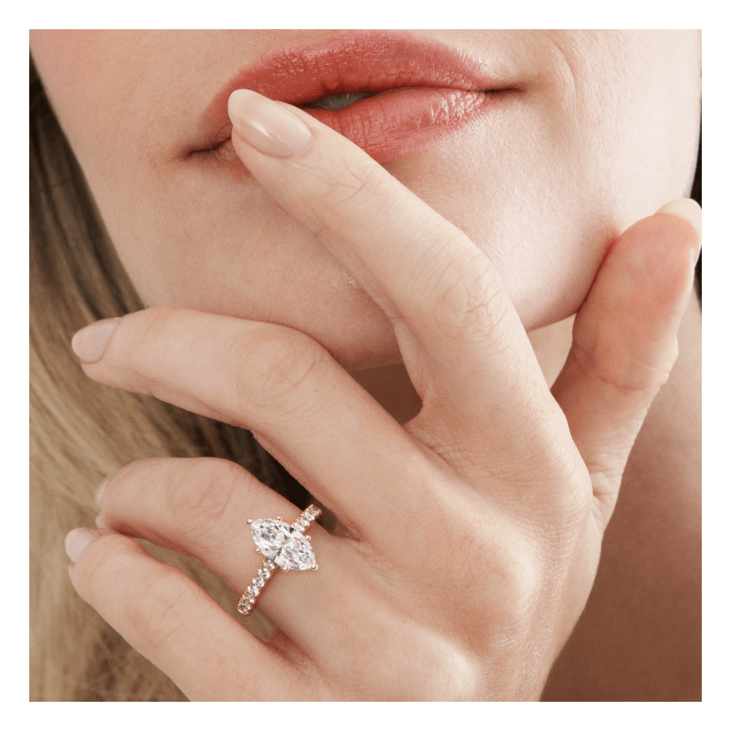 Close-up of a woman’s hand wearing a marquise-cut diamond engagement ring on a diamond-accented band.