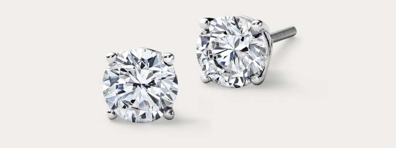 White gold round diamond stud earrings in four-prong setting.