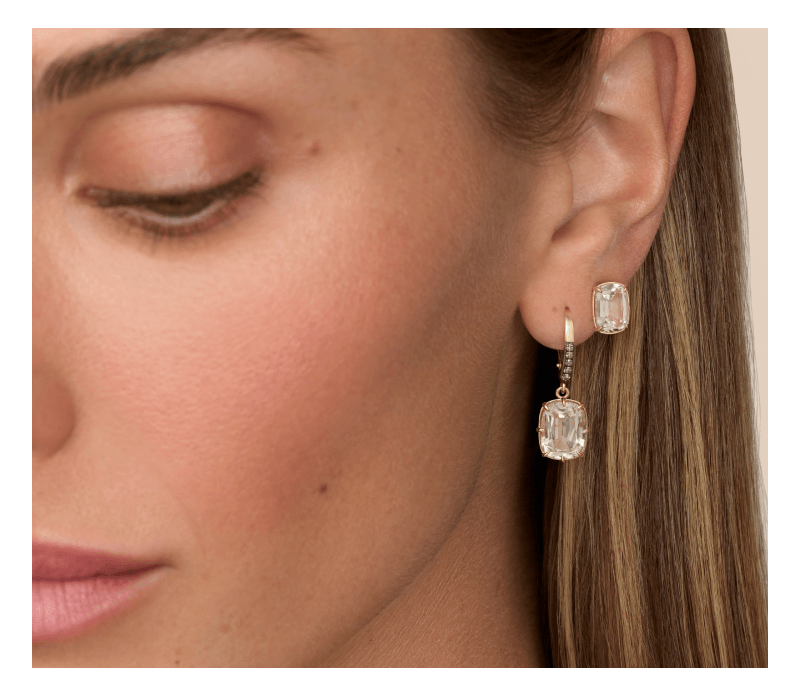 Gold drop and stud earrings featuring cushion-cut clear gemstones, with diamond accents on the drop earrings.