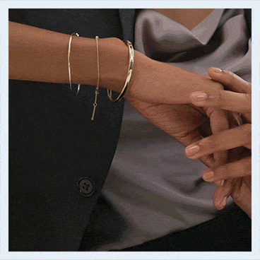 A model wearing stacked gold and diamond bracelets, a radiant-cut engagement ring and gold hoop earrings.