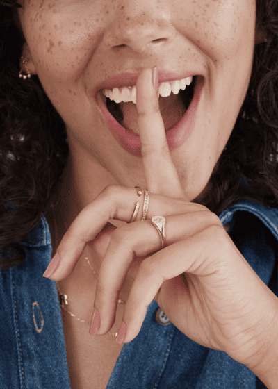 Woman wearing dainty yellow gold jewelry with diamond accents.
