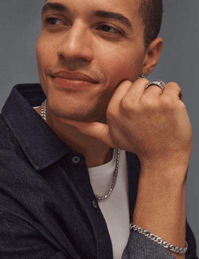 Man wearing a silver chain necklace, diamond stud earring and ring.