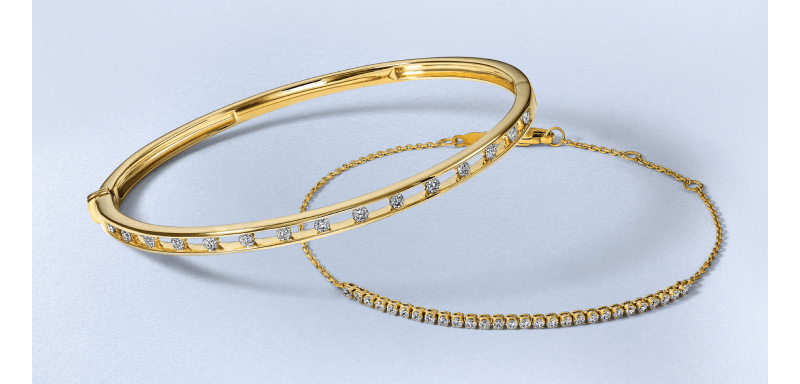 A yellow gold bangle and tennis bracelet accented with round diamonds.