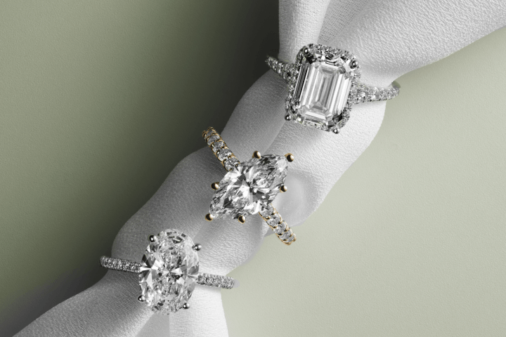 Oval, marquise and emerald-cut engagement rings with diamond-accented bands.