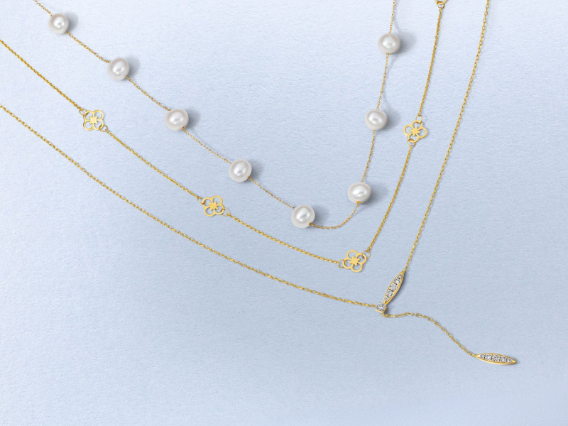 Layered yellow gold necklaces featuring pearls, clover motifs and diamond accents.