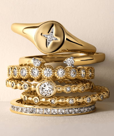 Yellow gold diamond rings including a compass-style signet ring, solitaire and pavé stackable bands.
