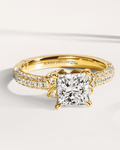 A yellow gold ring with princess cut diamond and pavé diamond band.