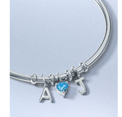 Silver charm bracelet with initial charms and a blue topaz heart-shaped gemstone.