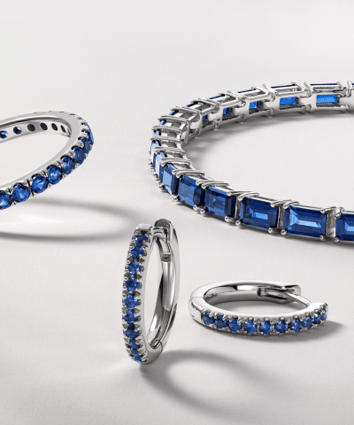 Blue gemstone tennis bracelets, hoop earrings and rings in white gold with diamond accents.