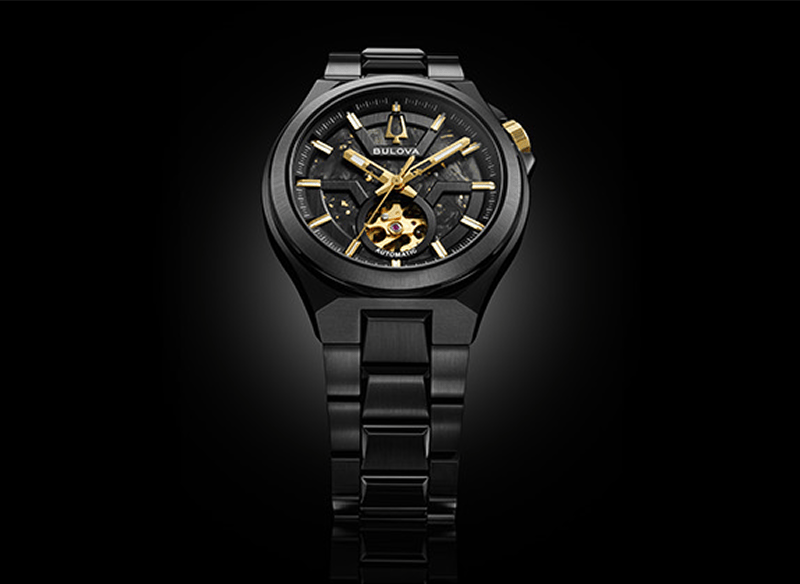 Black Bulova Maquina automatic watch with gold-tone accents and an open-heart dial.