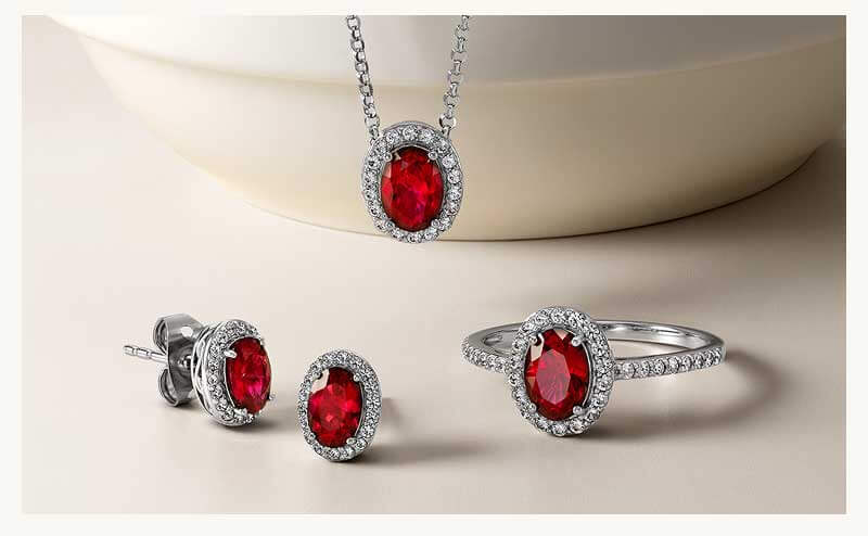 Set of diamond jewelry including studs, pendant chain & ring with ruby red gemstones.