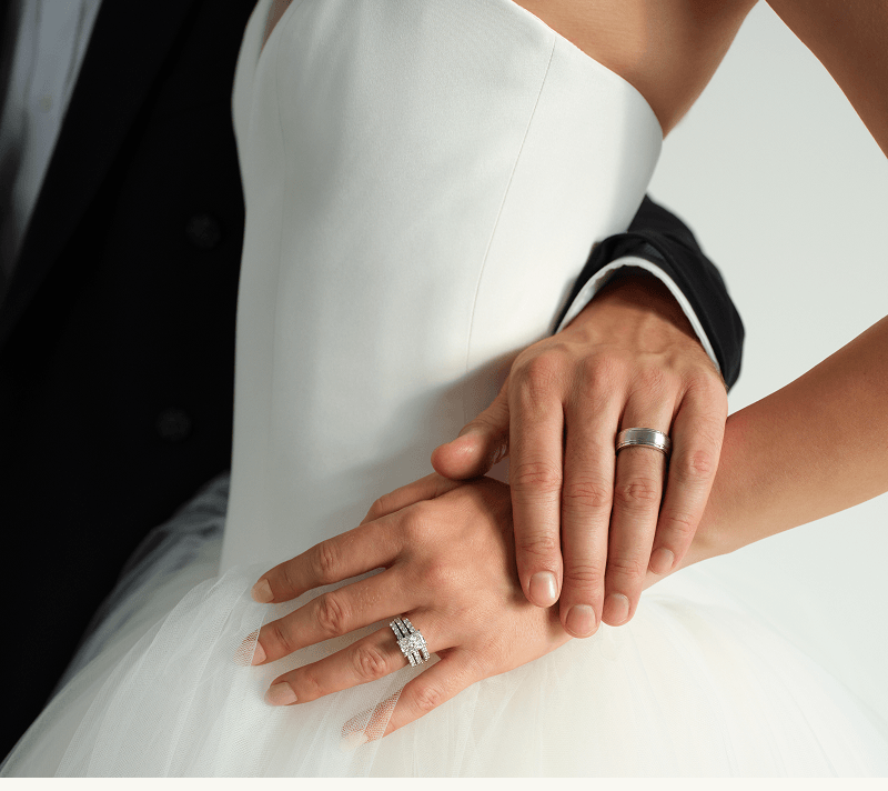 Bride & groom with focus on diamond ring, eternity band & male wedding band.