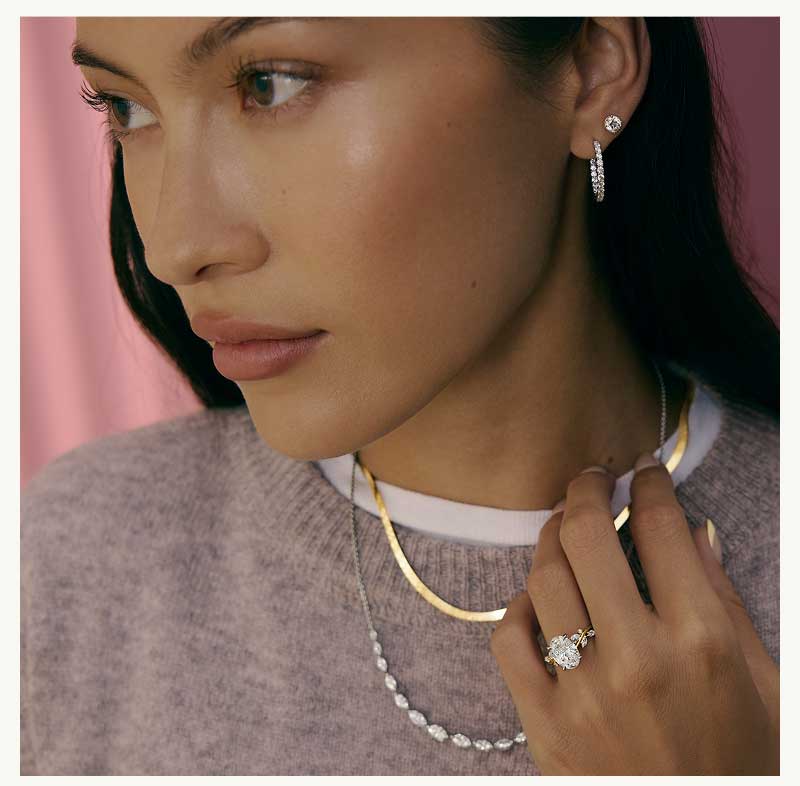 Model with oval diamond ring, gold & silver necklaces, diamond hoop & stud.