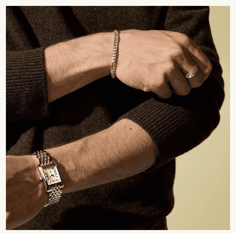 A model wearing a watch and gold jewelry. 