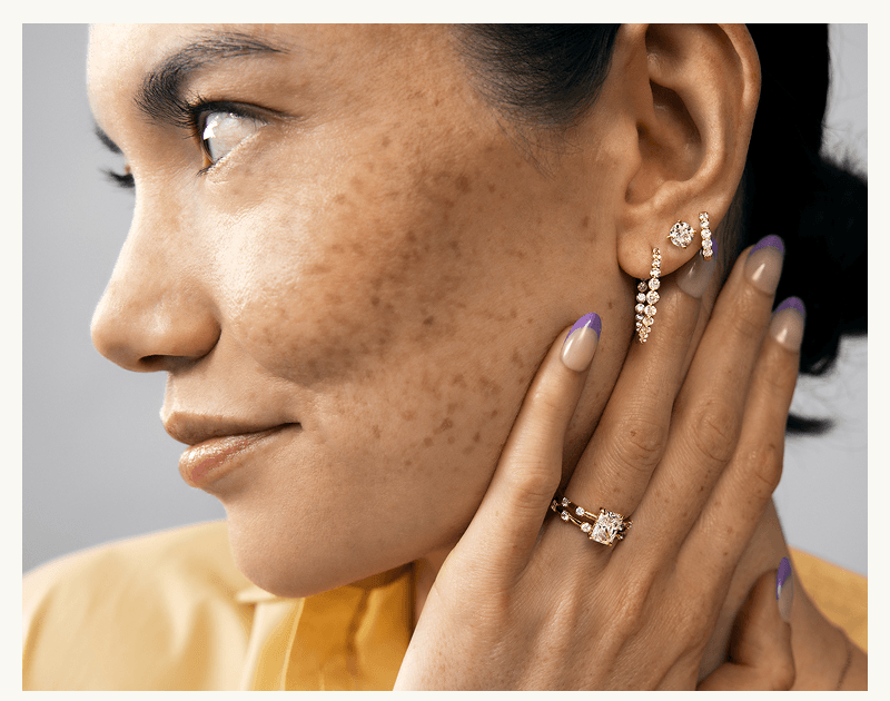 Model wearing diamond ring & ear stack, with hoops, huggies & solitaire stud.