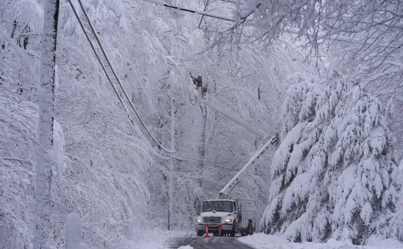A utility worker repairs powerlines on a snow-covered street