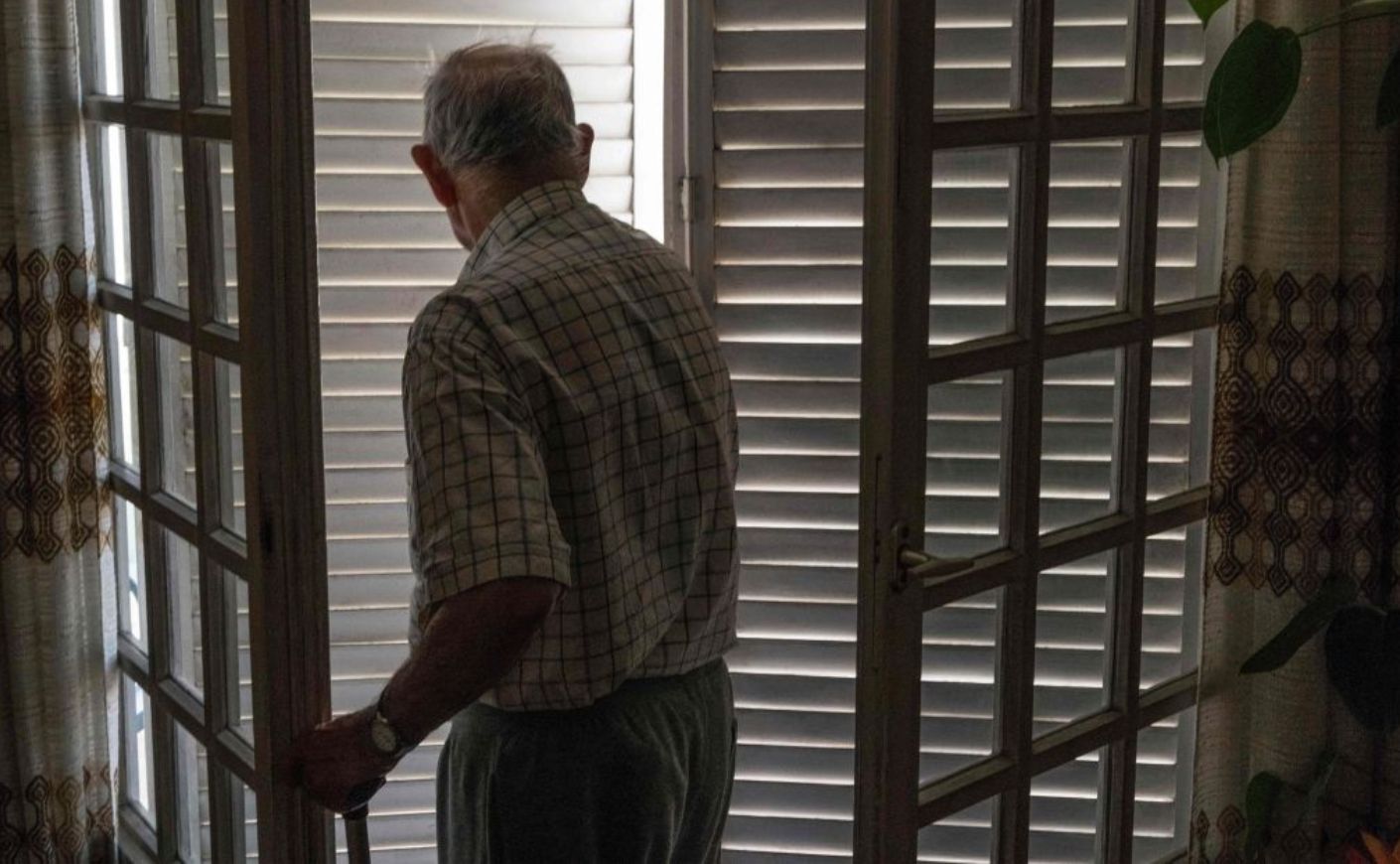 Older man walks through a door. 