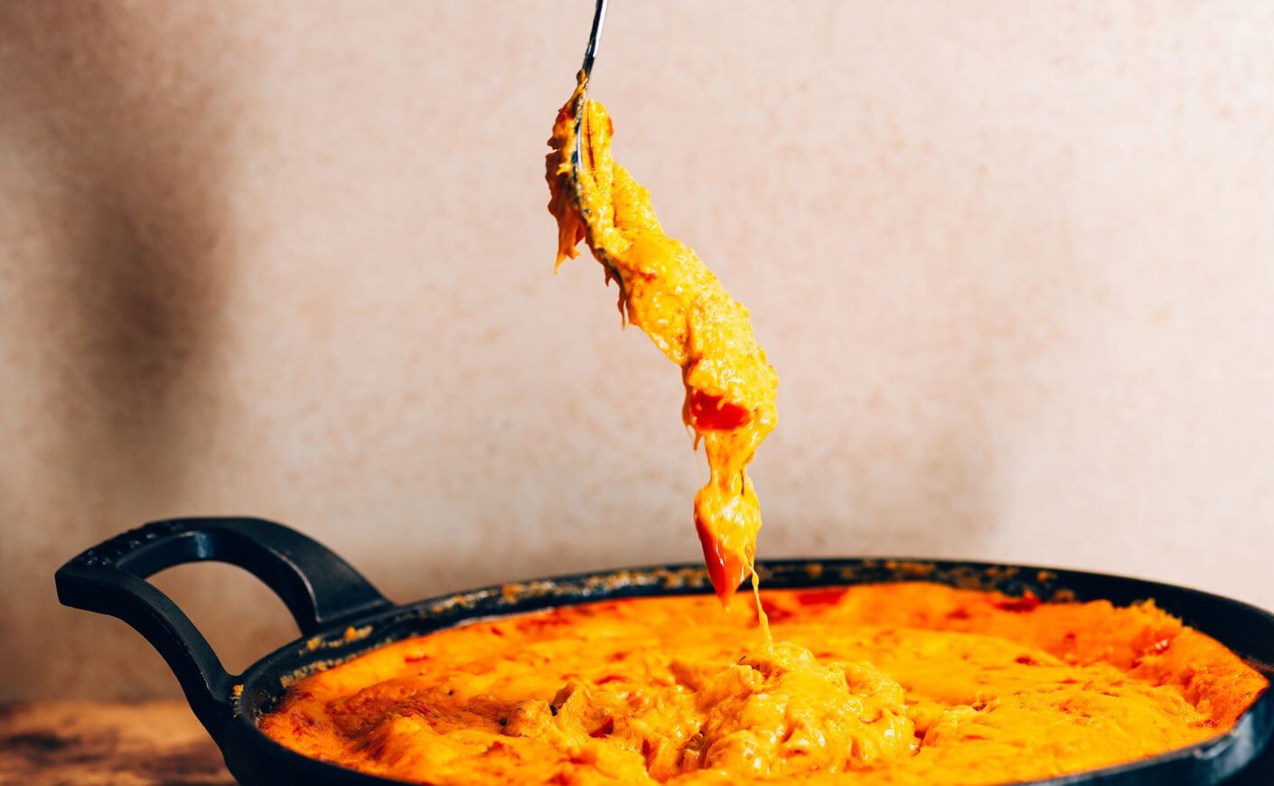 A fork dipping into a chile cheese dip