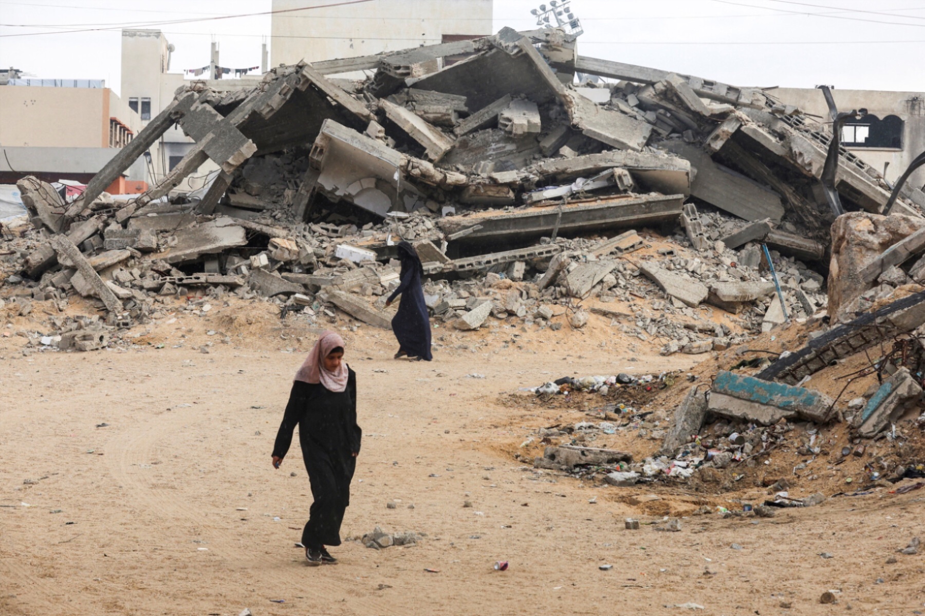 Palestinian women walk near rubble in Khan Younis after U.S. President Donald Trump announced that Israel and Hamas agreed on the first phase of a Gaza ceasefire.