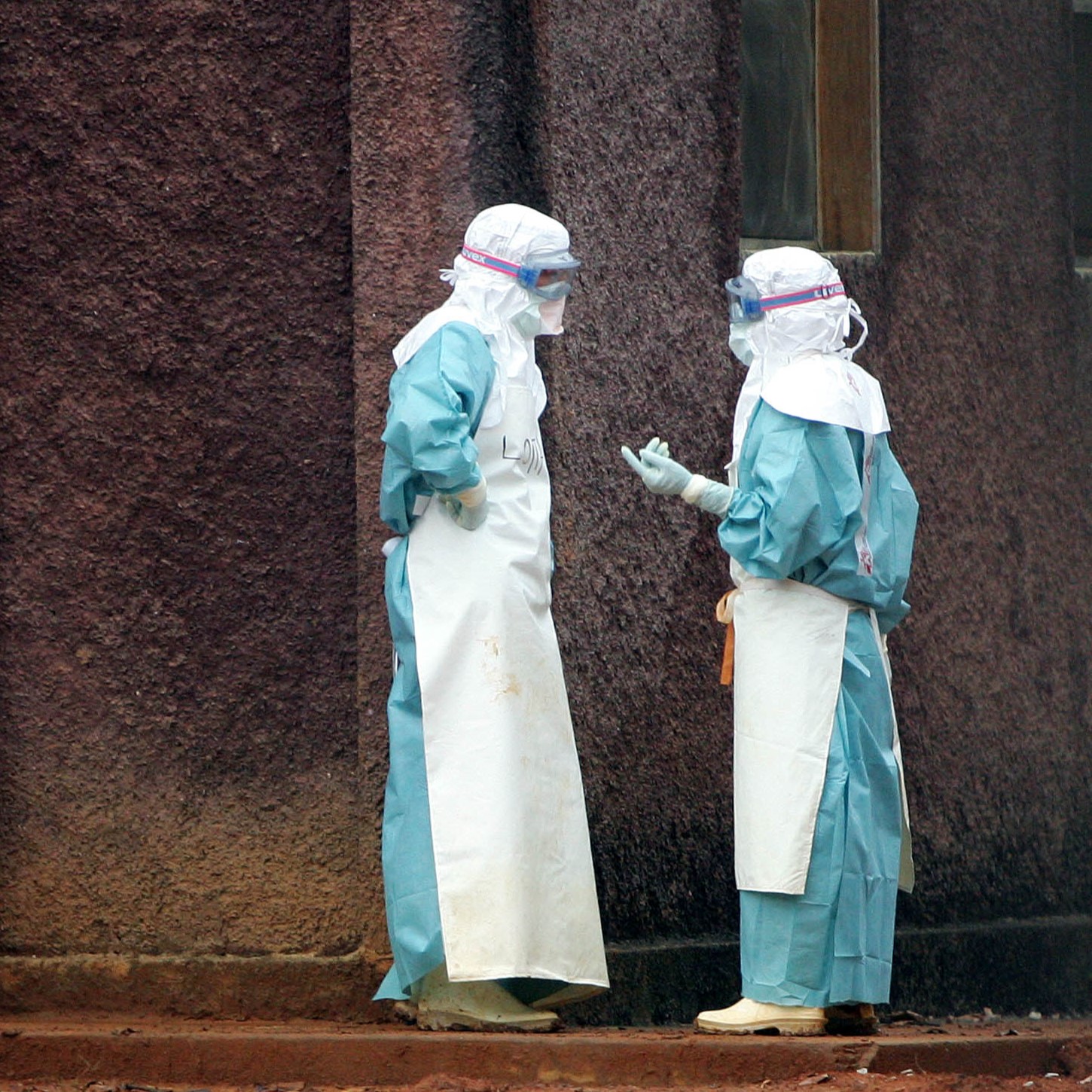 Health workers in protective clothing confer behind barriers marking the isolation ward where victims Marburg virus are treated, in Uige, Angola, on April 20, 2005.