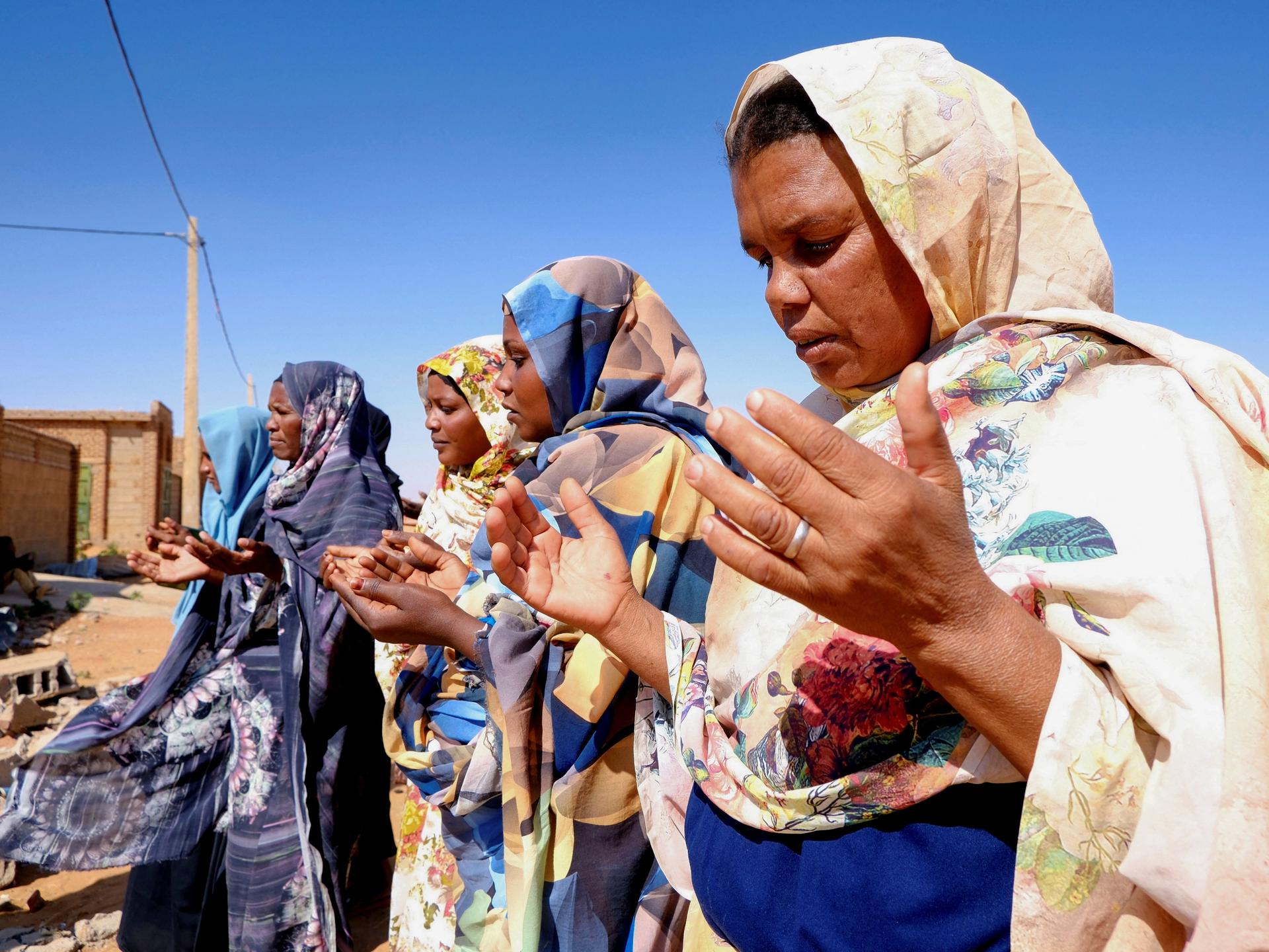 Women pray in front of a house struck by a drone, in El-Obeid, North Kordofan state, Sudan, on January 12, 2026.