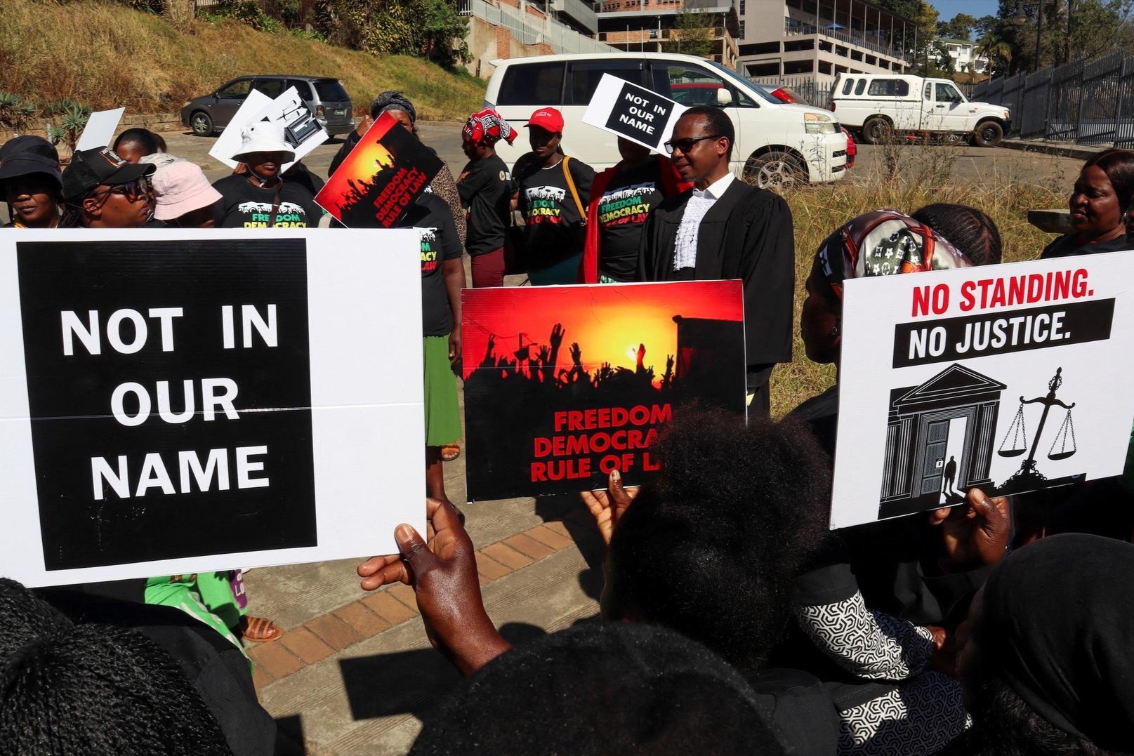 Protesters against an agreement to accept third-country deportees hold placards as lead applicant and lawyer Mzwandile Masuku addresses them outside the court in Mbabane, Eswatini on August 22, 2025.