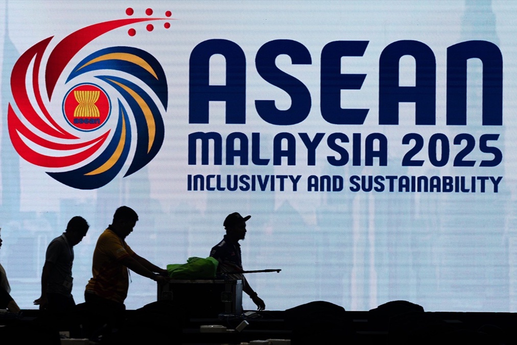 Workers walk past an electronic an ASEAN banner in Kuala Lumpur, Malaysia.