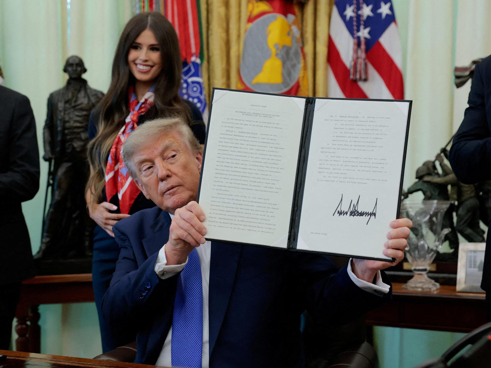 U.S. President Donald Trump displays a signed executive order regarding vaccine flexibility, in the Oval Office at the White House, in Washington, DC, on August 10, 2026.