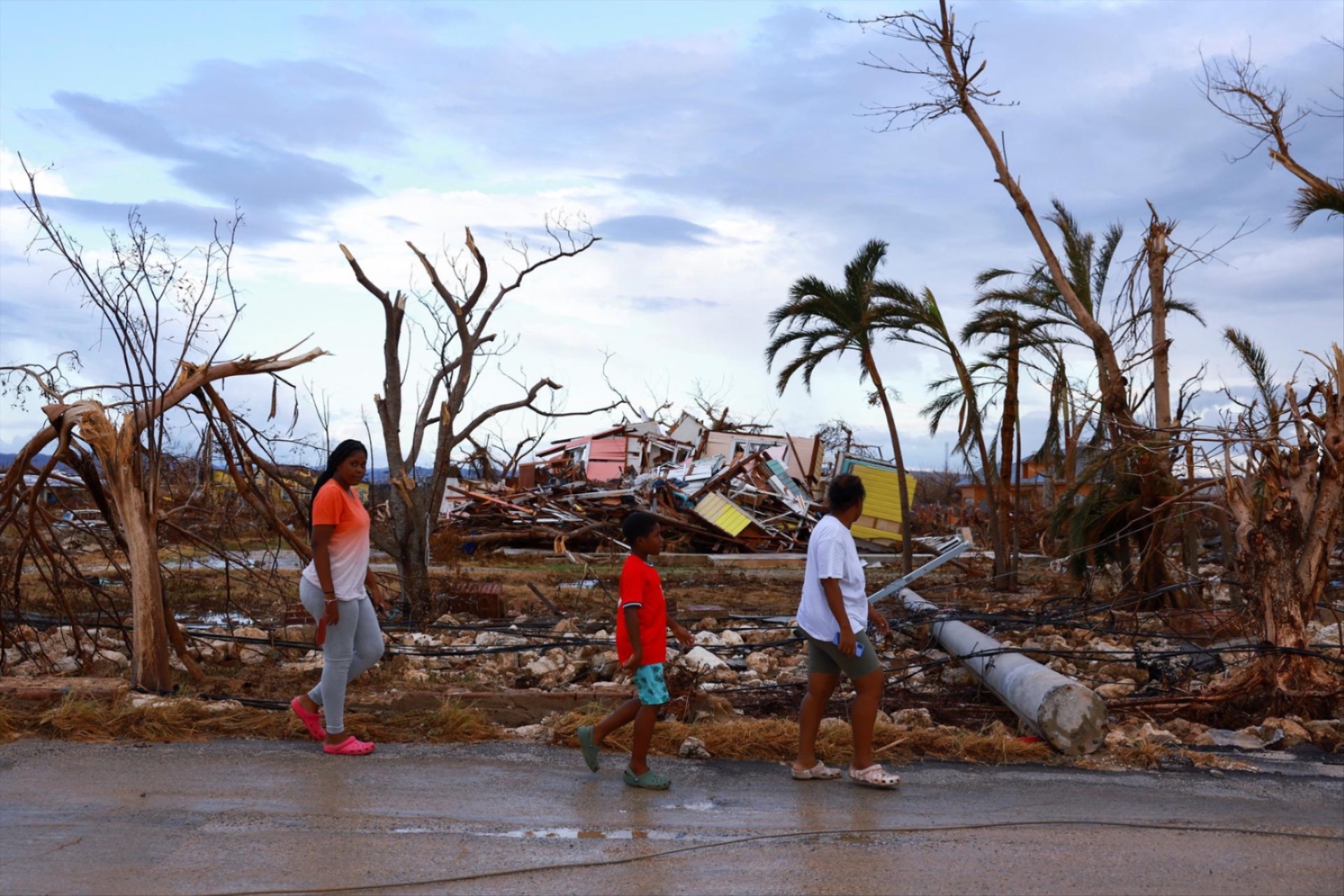 People walk past damaged houses in the aftermath of Hurricane Melissa, in Black River, Jamaica, November 5, 2025.