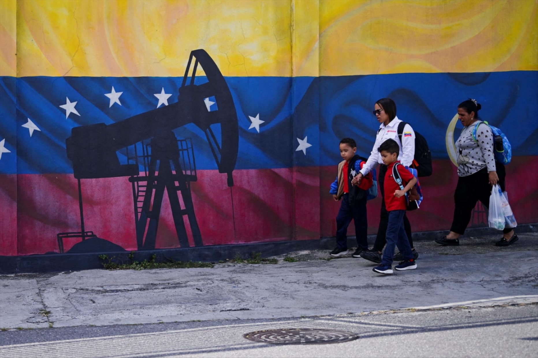 People walk past a painting of an oil pump on Venezuela’s national flag, in Caracas, Venezuela, January 13, 2026.