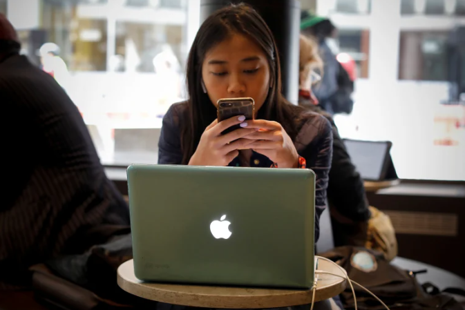 A woman uses her Apple iPhone and laptop in a cafe in lower Manhattan in New York City REUTERS/Mike Segar