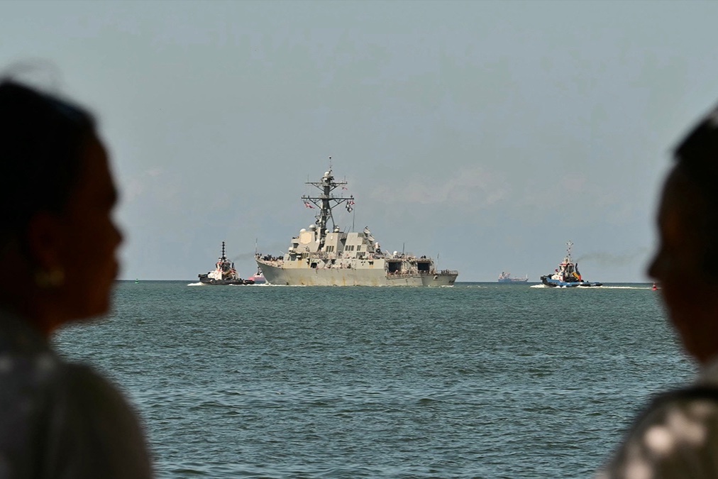 People watch the USS Gravely, a U.S. Navy warship, departing the Port of Spain on October 30, 2025.