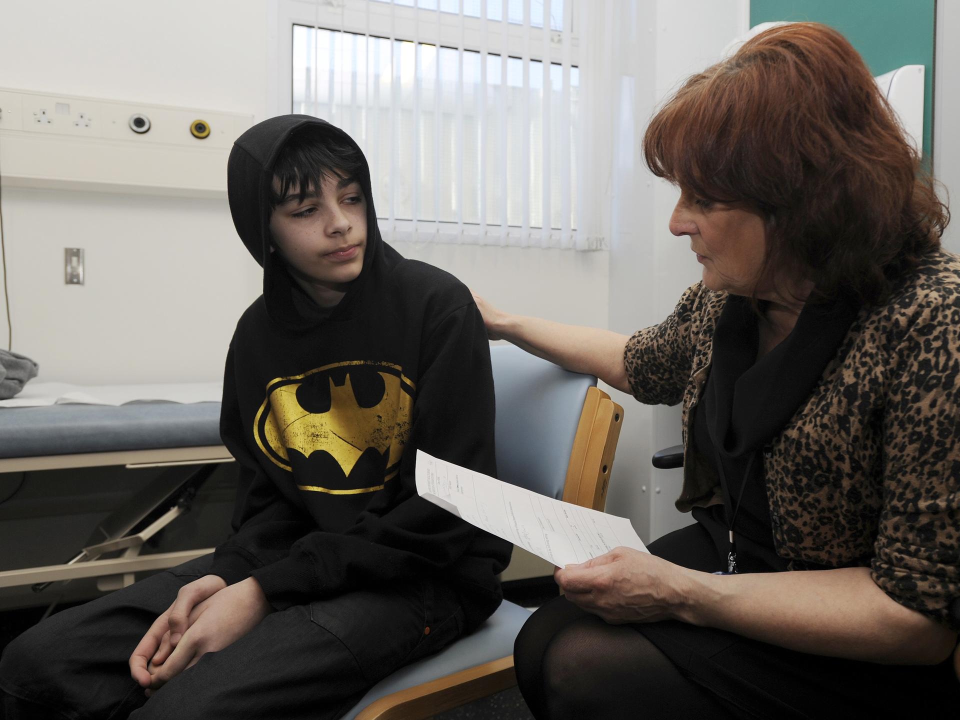 School Nurse Carolyn Rees talks to Kieran Elford, age 13, about the MMR vaccine, at Morriston Hospital's pediatric outpatients department, in Swansea, South Wales, on April 6, 2013. 