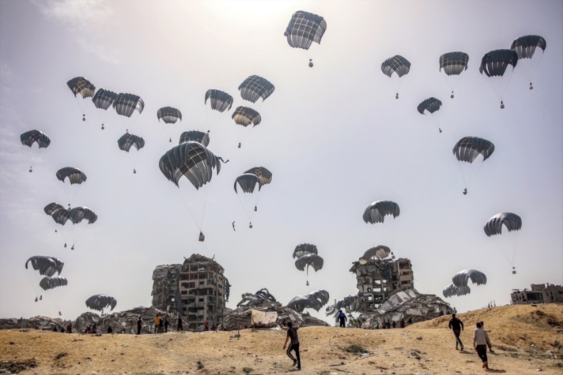 Palestinians rush to accept the parachuting humanitarian aid packages dropped over the northern Gaza Strip on April 23, 2024. 