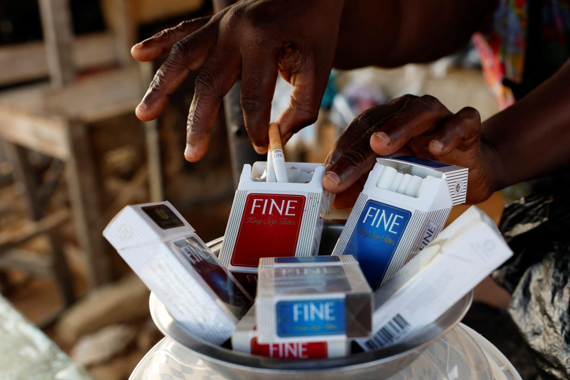 A street vendor selects cigarettes for a customer, in Abidjan, Ivory Coast, on May 27, 2024. 