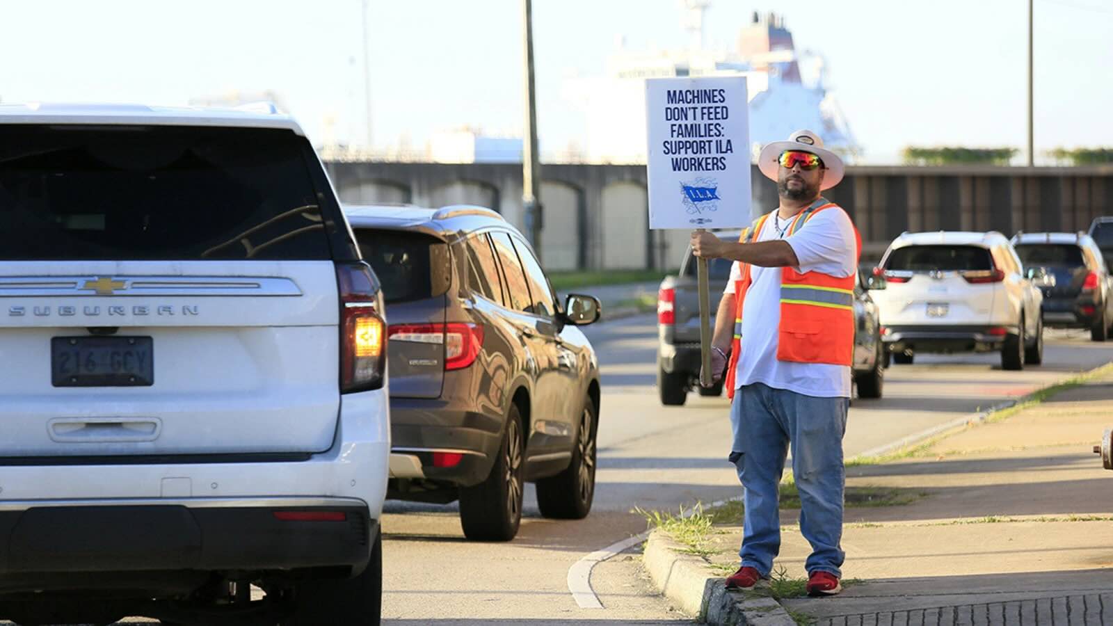 A striking port worker stands at the entrance to the Port of New Orleans, Louisiana, on October 2, 2024. About 45,000 dock workers walked out at 36 U.S. ports amid fears of job loss in an AI-driven future.