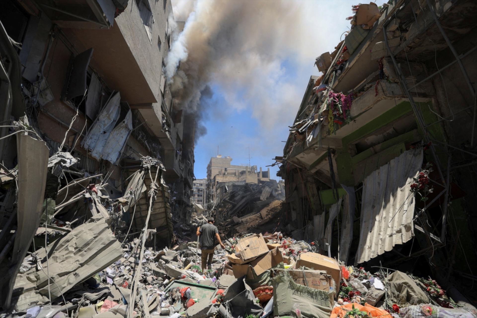 Smoke rises as a Palestinian man inspects the site of Israeli strikes on buildings at Gaza's Old City market, July 9, 2025.
