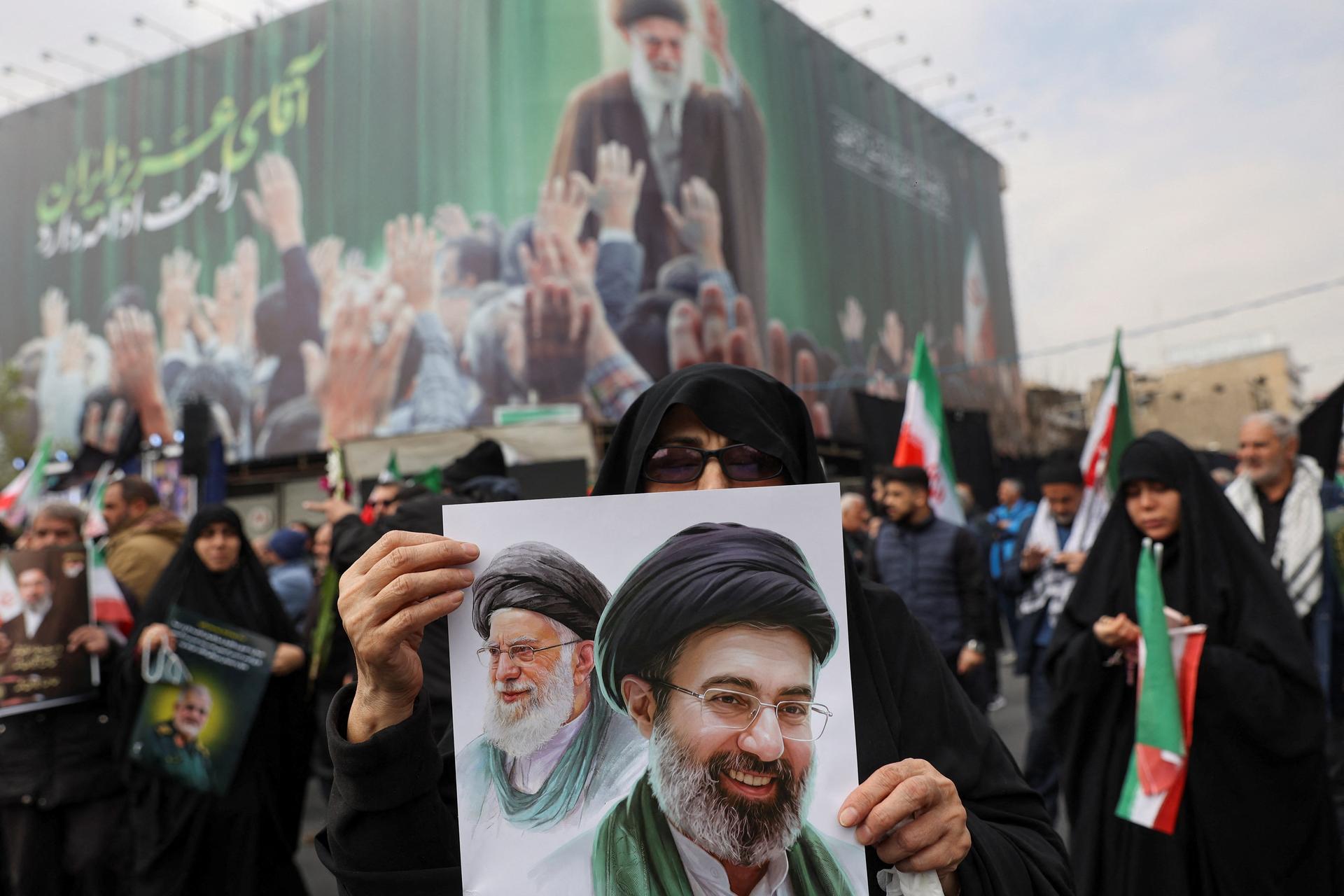 A woman holds an image of Iran's new supreme leader, Mojtaba Khamenei, alongside late Iranian Supreme Leader Ayatollah Ali Khamenei, during a funeral ceremony for the Iranian military commanders who were killed in strikes, amid the U.S.-Israeli conflict with Iran, in Tehran, Iran, March 11, 2026.